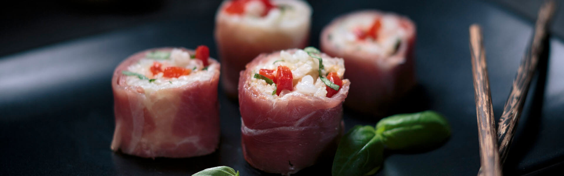 Italian Sushi with arborio rice and red bell peppers rolled in prosciutto