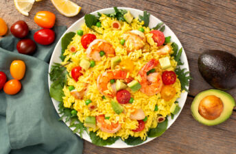 White bowl with paella salad, diced avocados, cherry tomatoes, shrimp, chicken and olives