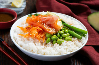 Poke bowl with sushi rice, salmon, asparagus, avocado, miso, edamame, sesame and orange