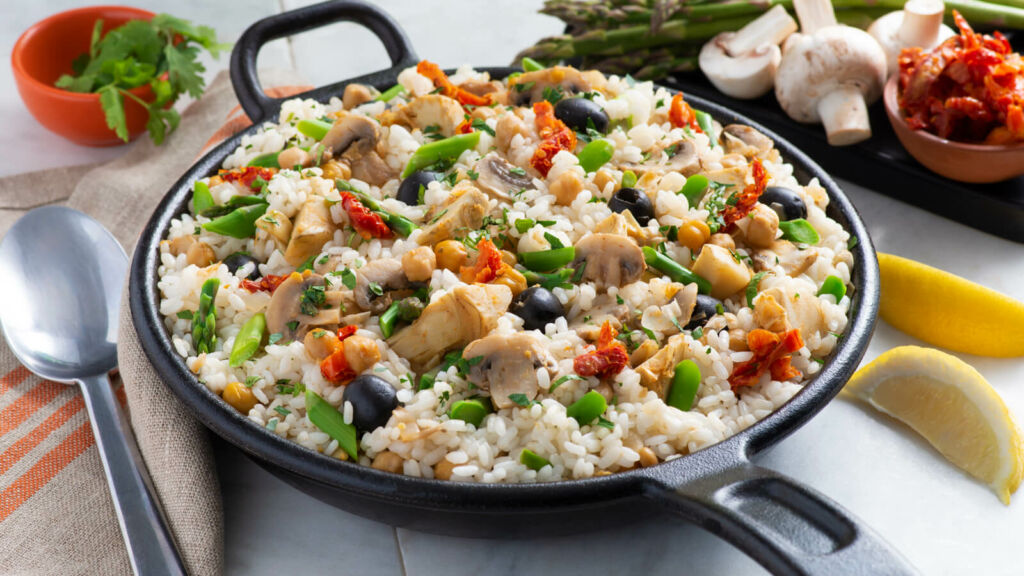 Skillet with vegetarian paella, black olives, mushrooms, artichokes and paprika